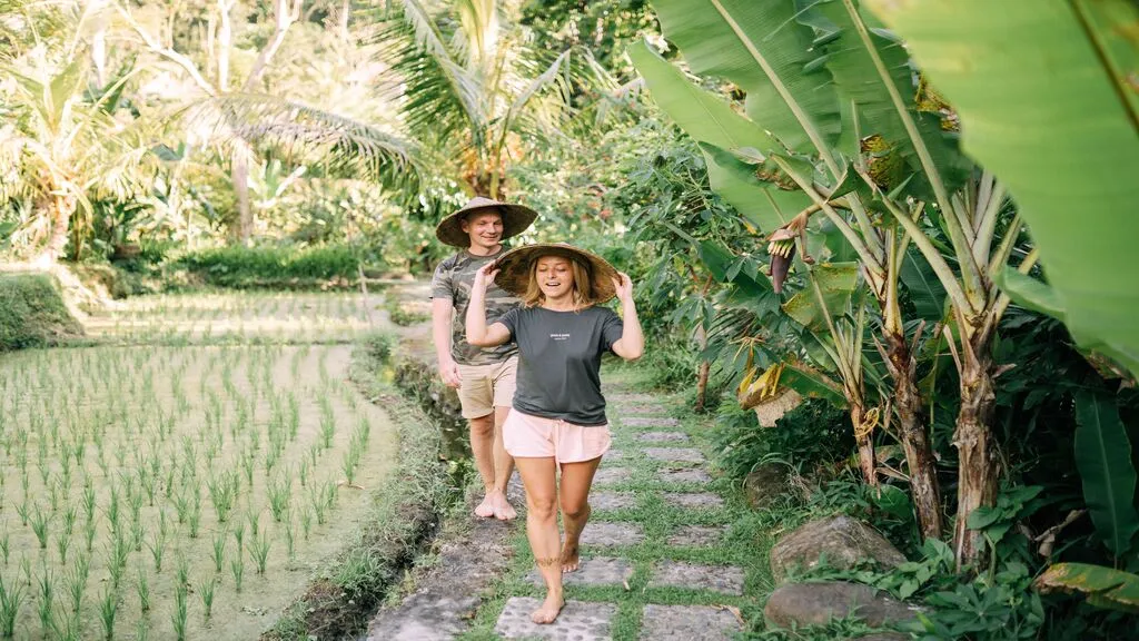 Two guests explore lush tropical rice terraces along a scenic village path, embracing an authentic countryside experience.