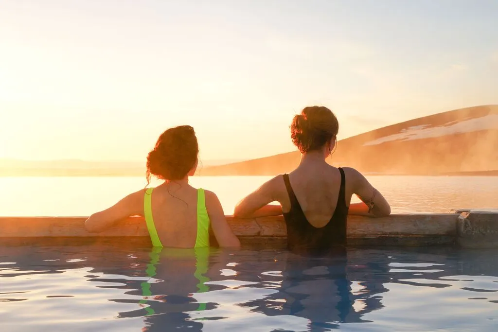 Women soaking in a natural hot spring during sunset