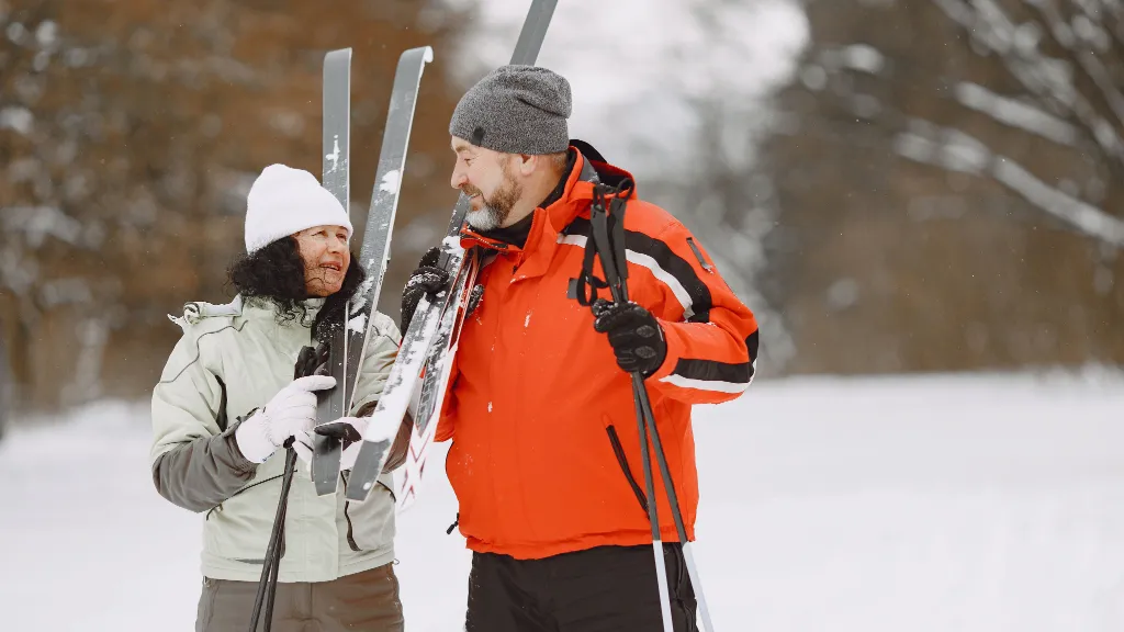 Couple in winter attire holding skis