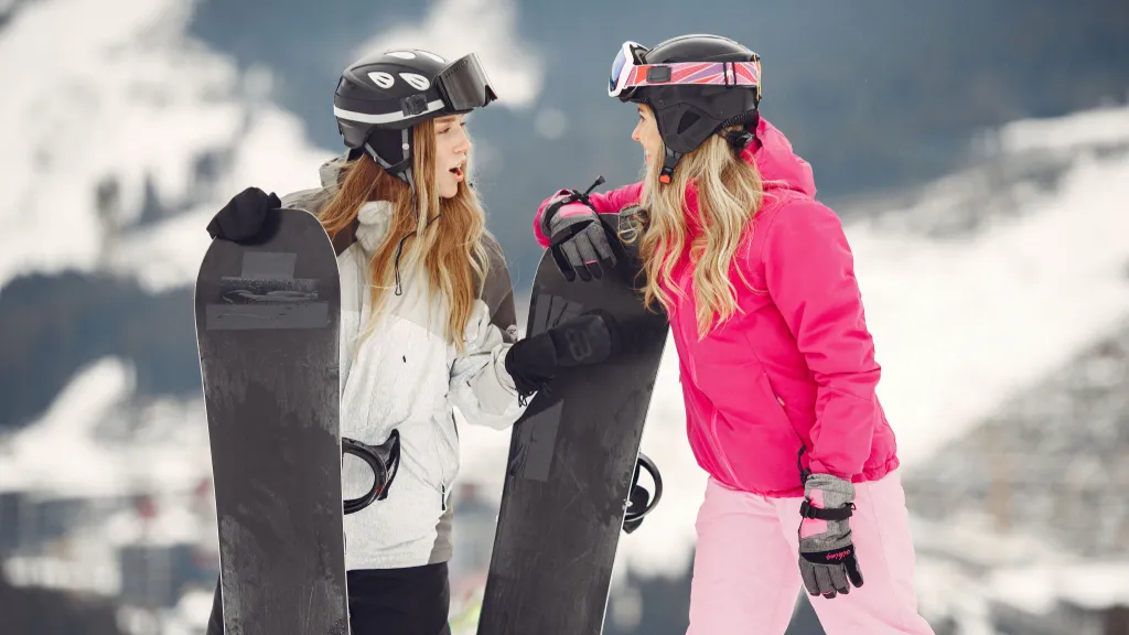 Female snowboarders with ski gear on snowy mountain