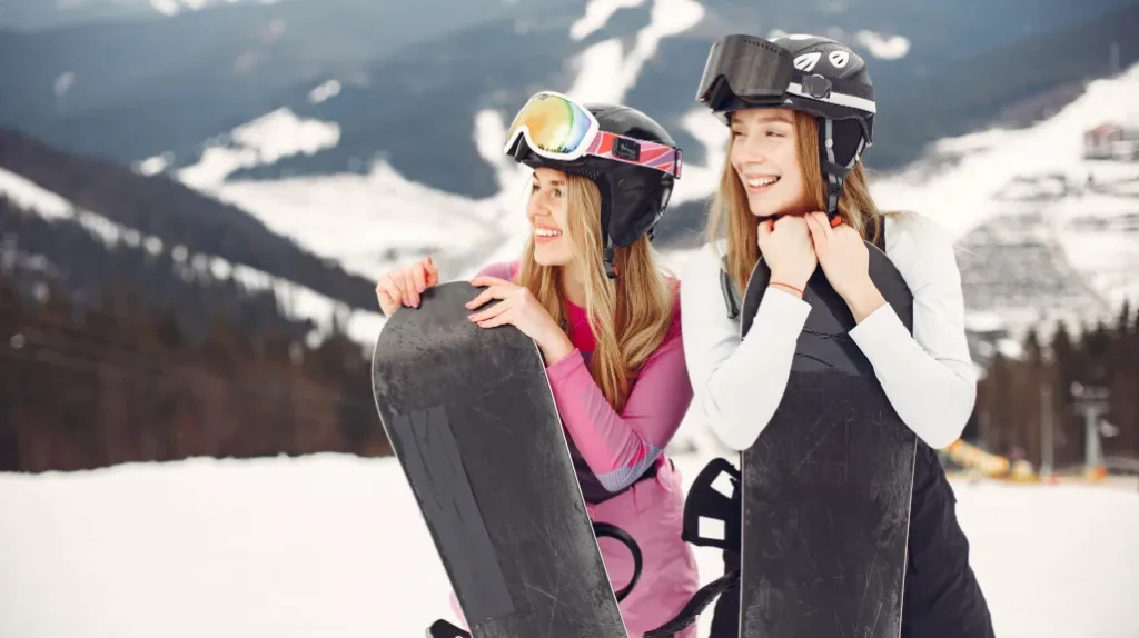 Smiling women holding snowboards on winter sports vacation