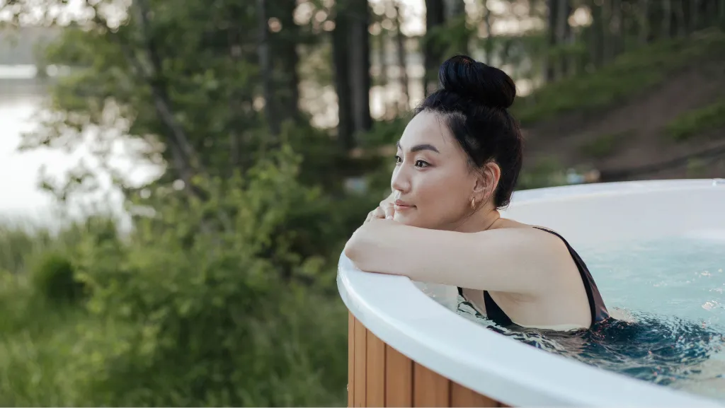 Woman relaxing in an outdoor hot tub surrounded by nature